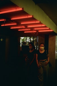 two people standing under a red neon light